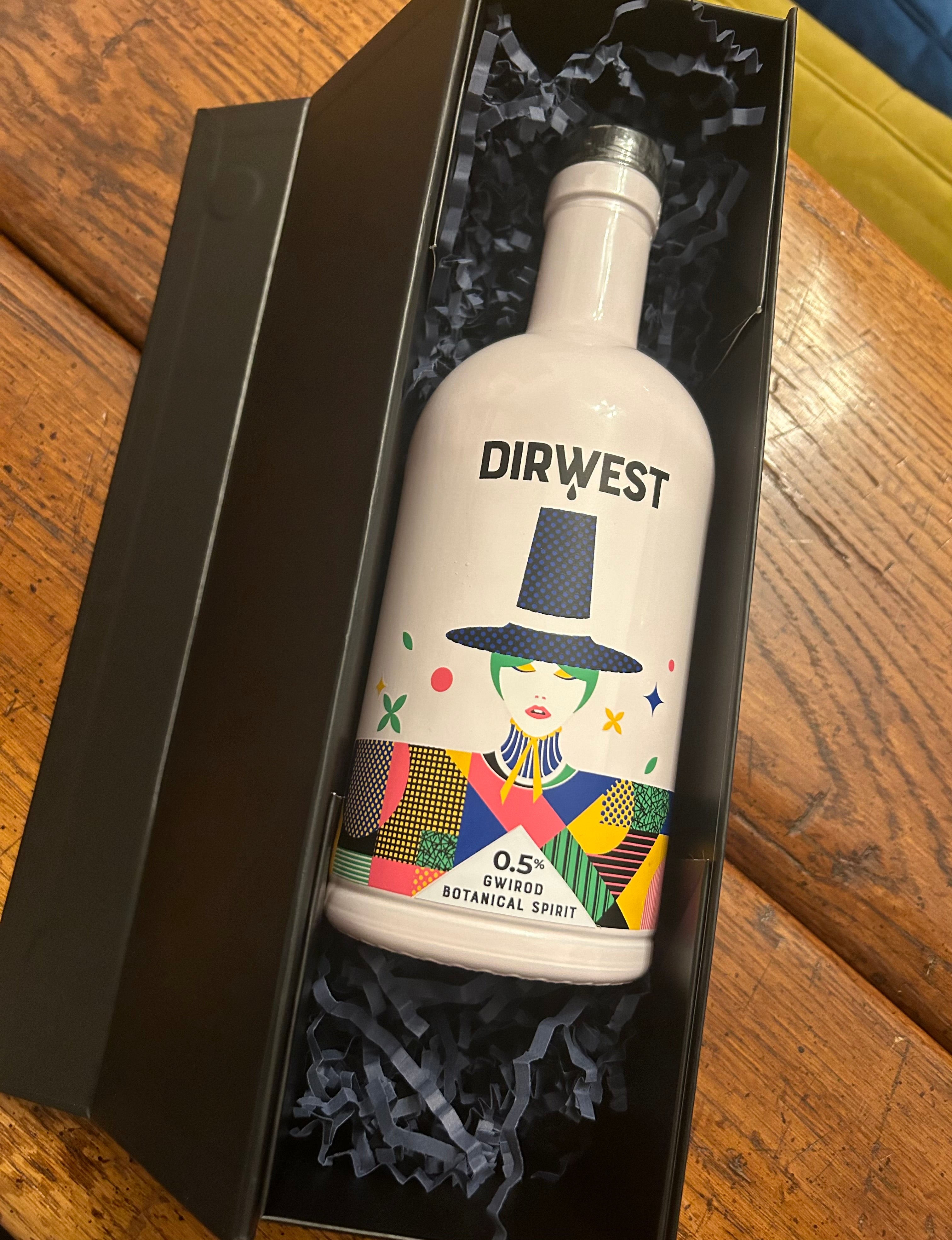 A bottle of Dirwest gin with a colorful, artistic label, presented in a black gift box with a bow on top.